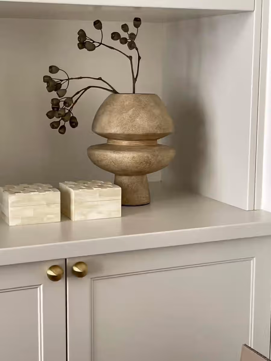 Sculptural stone vase and bone-inlay boxes on a built-in shelf