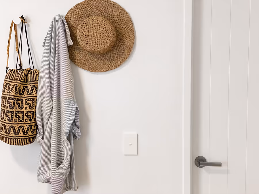 Woven bag, striped towel and a straw hat hung by the bedroom door