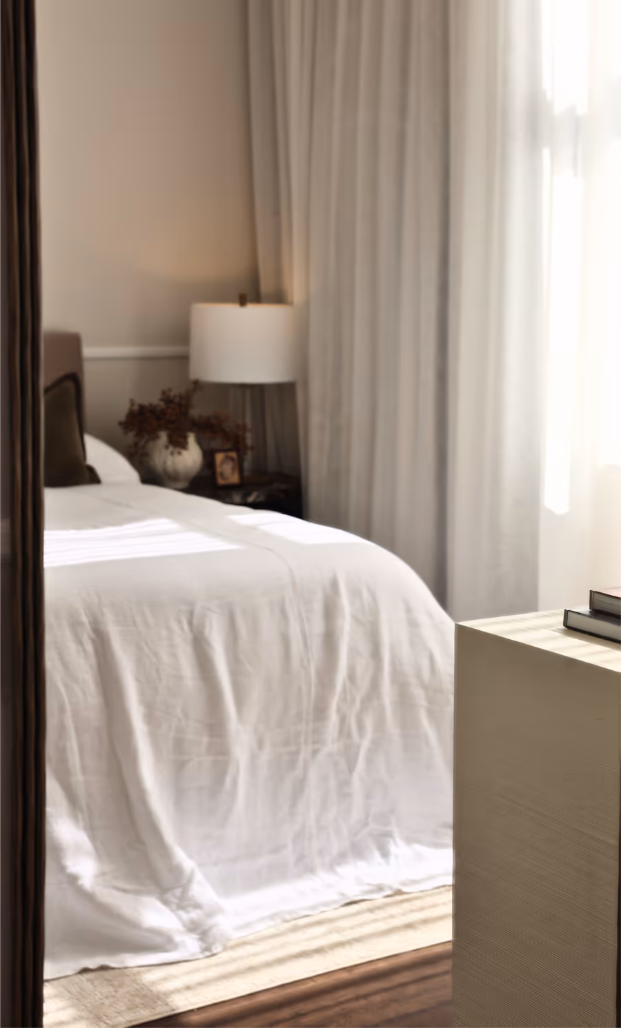 The bedroom reflected in a tall brass-framed mirror, lamp lit beside the bed