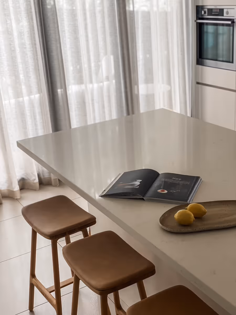 Tan leather stools at the stone island, an open book and lemons on a board